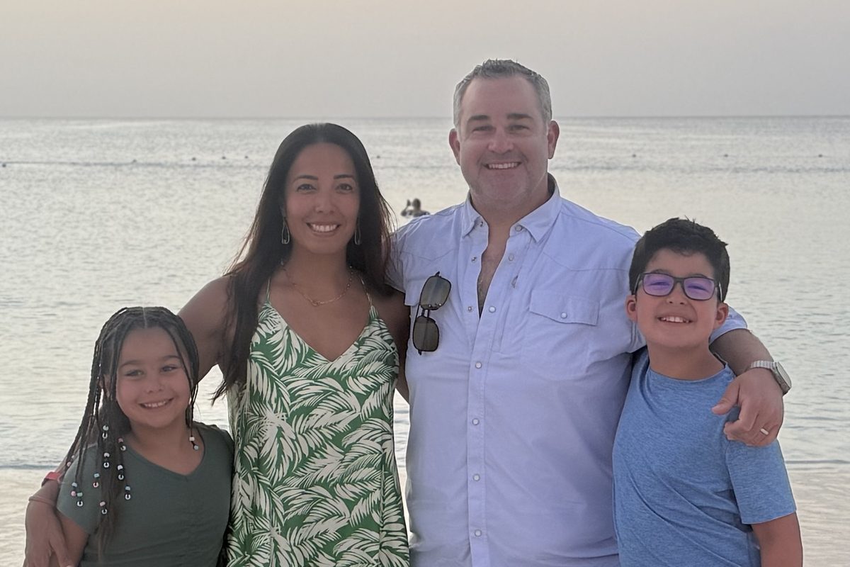 Dr. Christopher Bob with his wife and their two children on the beach